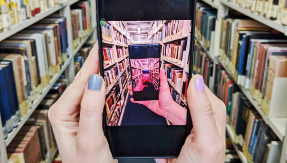 Mobile phone taking photo of library shelves.